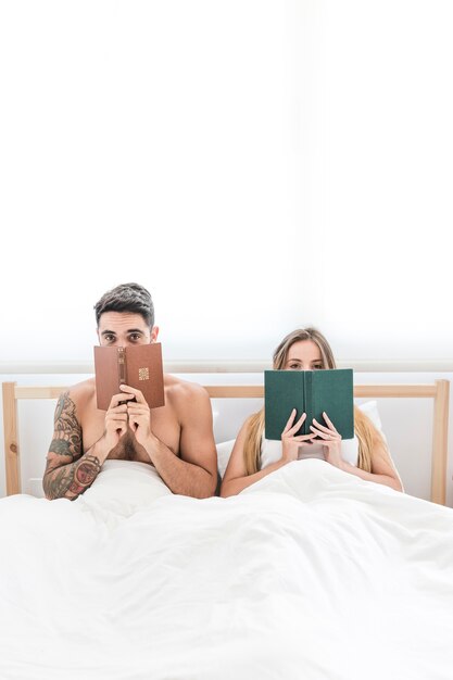 Pareja, sentado, en cama, mirar a escondidas, de, libro