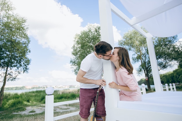 Pareja separada por una columna con una guitarra besándose