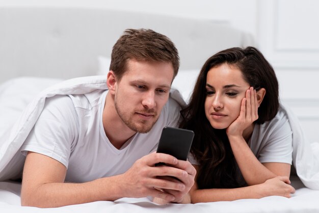 Pareja siendo adicta a las redes sociales en la cama