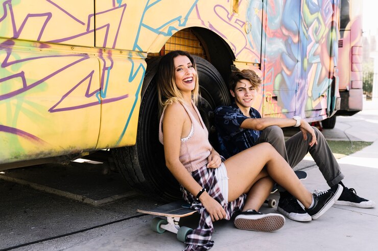 Foto gratuito pareja skater con estilo apoyada contra un autobús