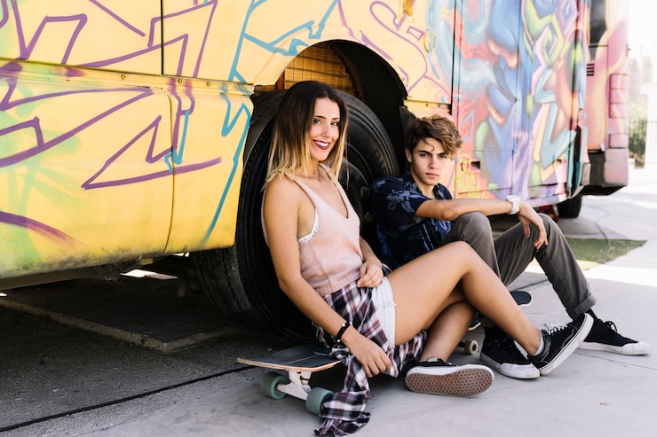 Foto gratuito pareja skater sonriente apoyada contra autobús