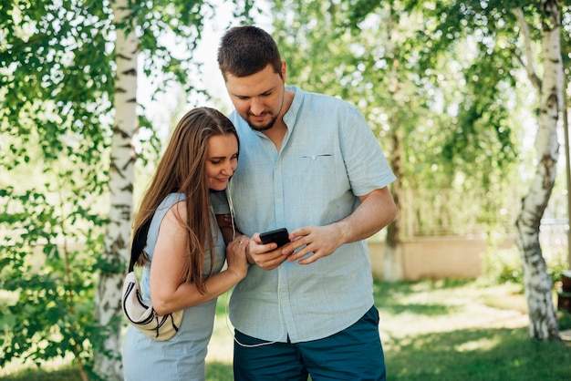 Foto gratuita pareja con smartphone en bosque de abedules