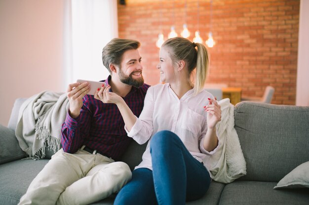 Pareja con smartphone en el sofá