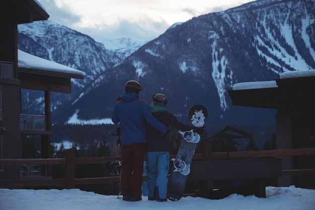 Foto gratuita pareja con snowboard de pie en campo cubierto de nieve