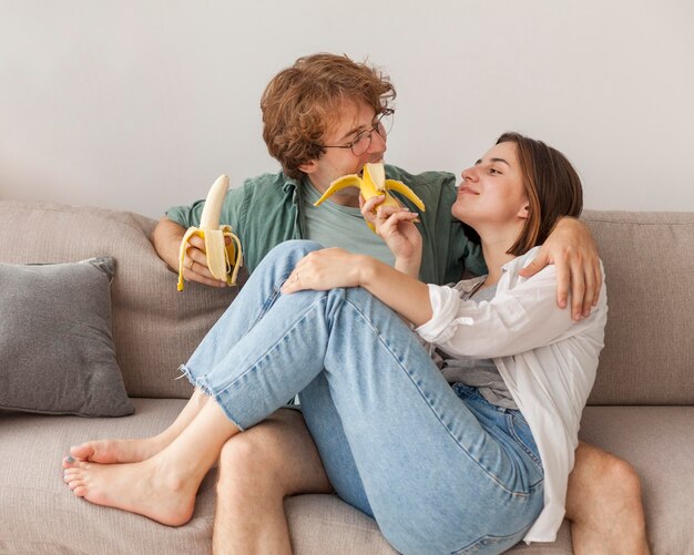 Pareja en el sofá comiendo plátanos