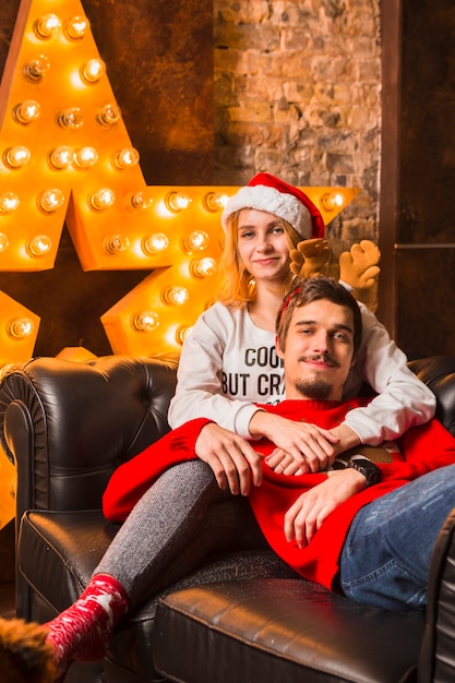 Pareja en sofá enfrente de decoración de estrella de navidad