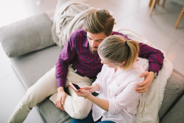 Pareja en el sofá con teléfono inteligente