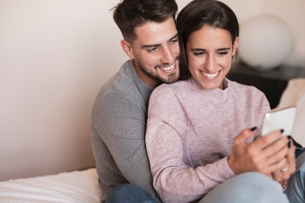 Pareja sonriendo al teléfono