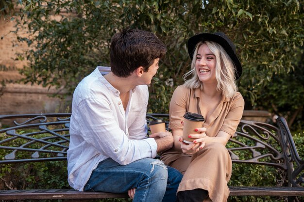 Pareja sonriendo y hablando en el banco en el parque