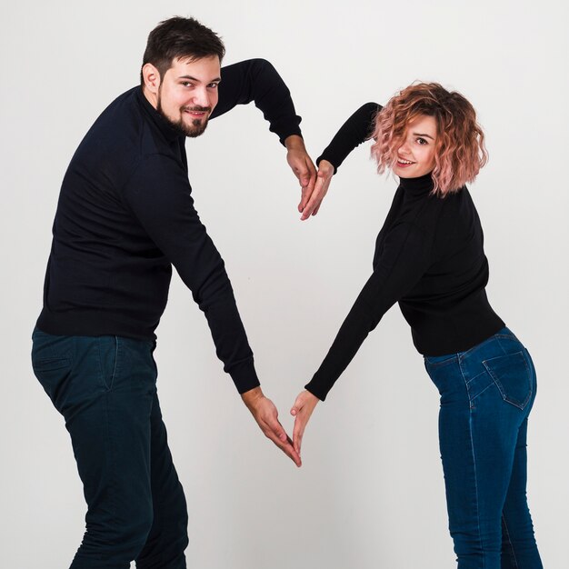 Pareja sonriendo y haciendo forma de corazón con brazos