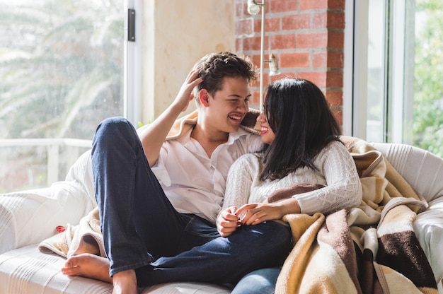 Pareja sonriendo tapados con una manta