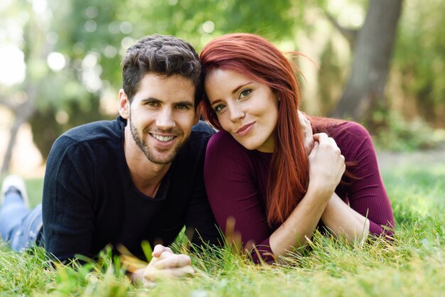 Pareja sonriendo tumbada en el césped