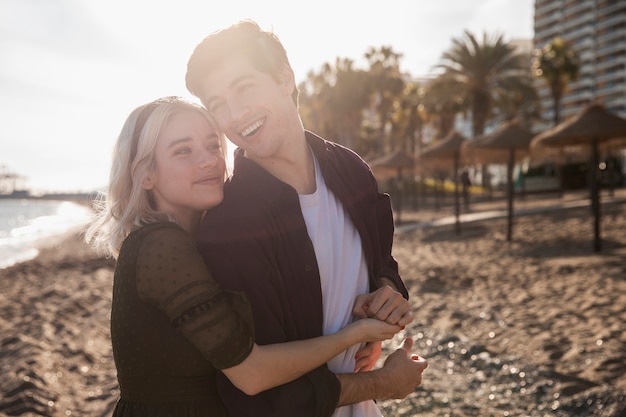 Foto gratuita pareja sonriente abrazada en la playa