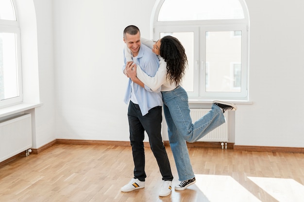 Pareja sonriente abrazada en su nueva casa vacía