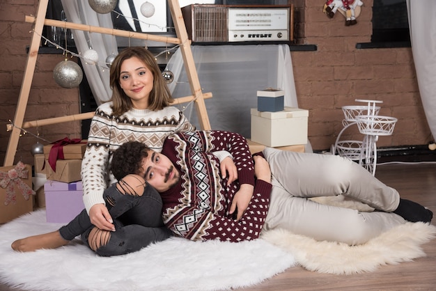 Pareja sonriente adorable joven sentada en el suelo y posando.