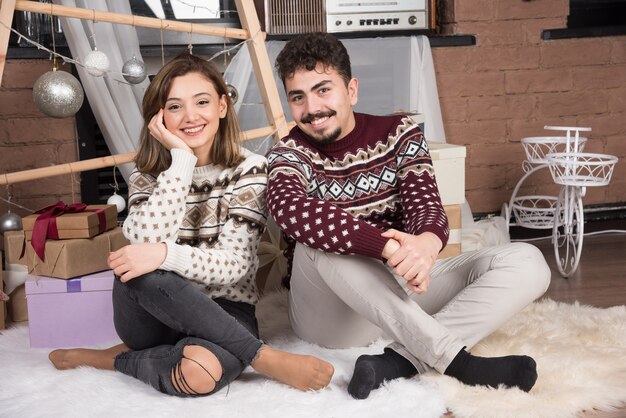 Pareja sonriente adorable joven sentada en el suelo y posando.