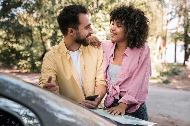 Pareja sonriente al aire libre con mapa y smartphone