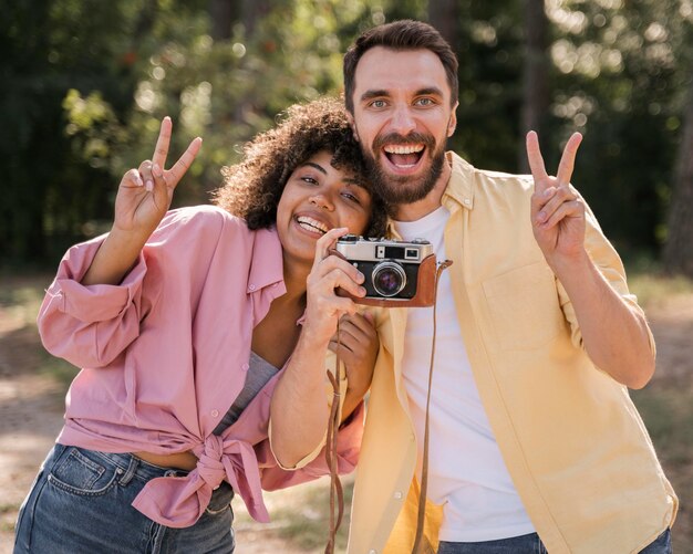 Pareja sonriente al aire libre tomando fotografías con cámara