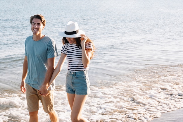 Pareja sonriente andando por la orilla