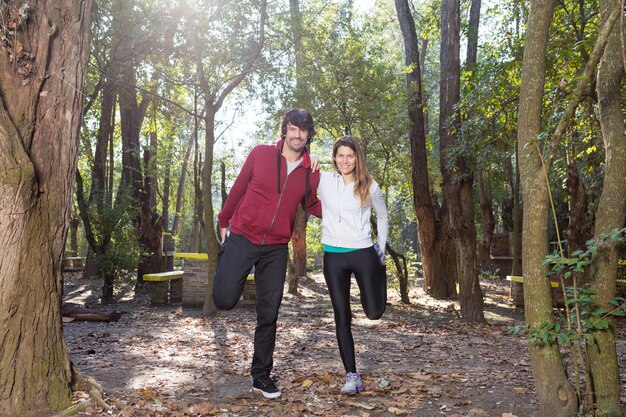 Pareja sonriente ayudándose a estirar el uno al otro