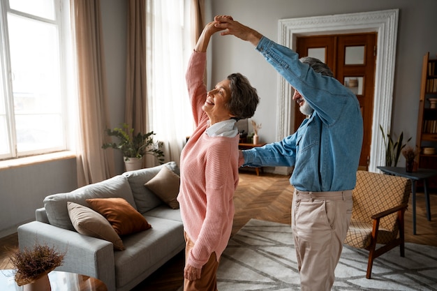 Pareja sonriente bailando en casa vista lateral