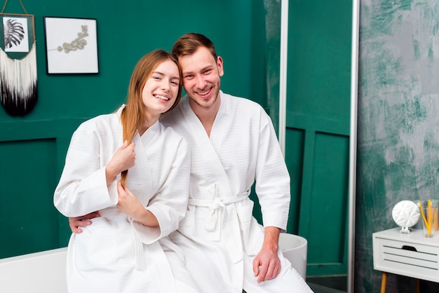 Pareja sonriente en batas de baño abrazados