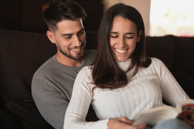 Foto gratuita pareja sonriente en casa leyendo tiempo