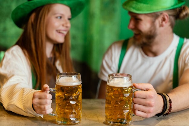 Pareja sonriente celebrando st. día de patricio con bebidas en el bar.