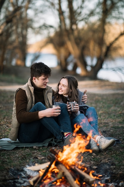 Pareja sonriente cerca de fogata