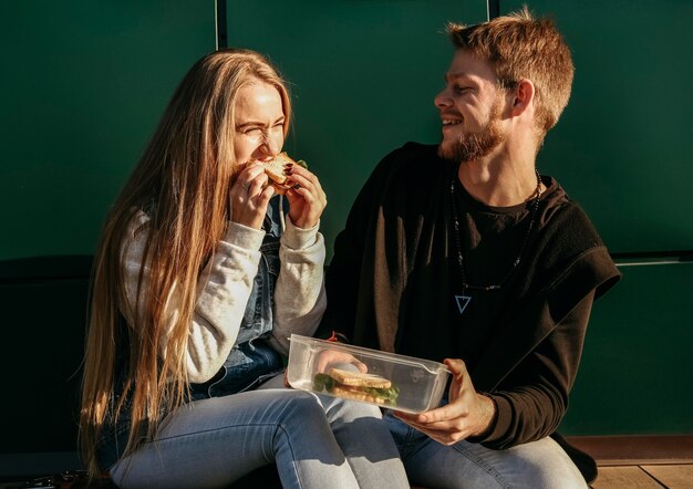 Pareja sonriente comiendo juntos al aire libre