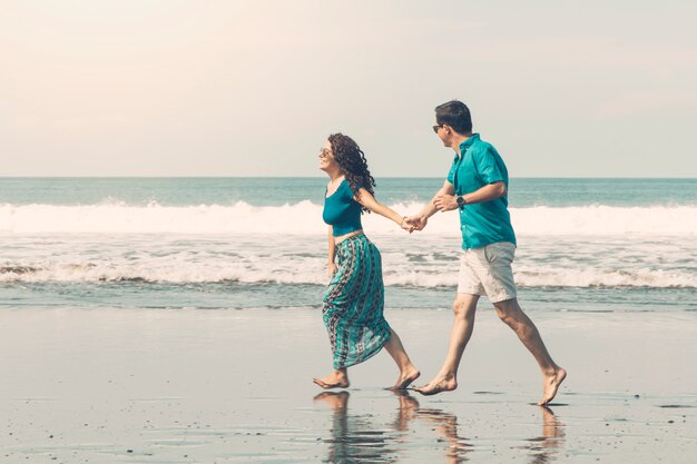 Pareja sonriente descalzo caminando por la playa