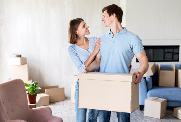 Pareja sonriente en el día de la mudanza con caja