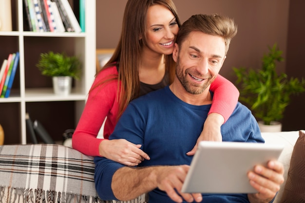 Pareja sonriente disfrutando de internet gratis en casa