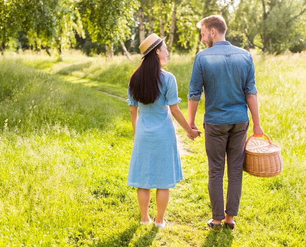 Pareja sonriente enamorada de pie en el camino del parque tomados de la mano