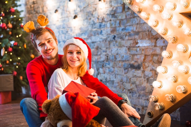 Pareja sonriente enfrente de árbol de navidad