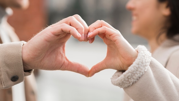 Pareja sonriente haciendo forma de corazón con sus manos