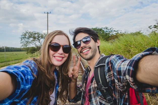 Pareja sonriente haciendo un selfie en vías de tren