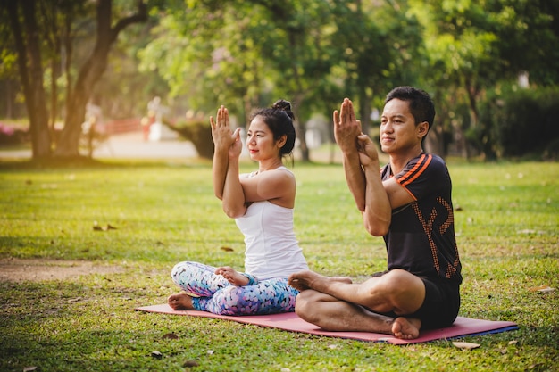 Pareja sonriente haciendo yoga en el parque