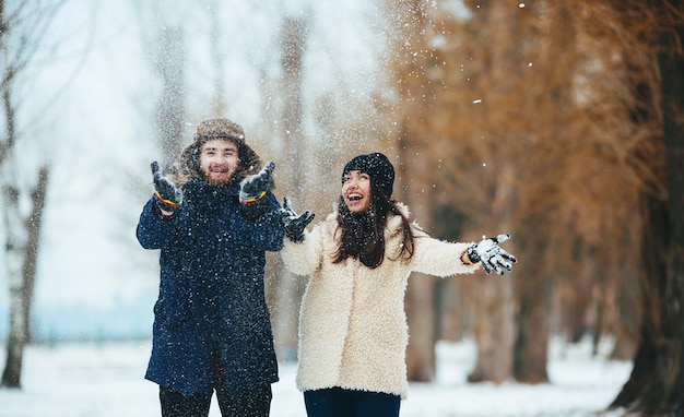 Pareja sonriente jugando con la nieve