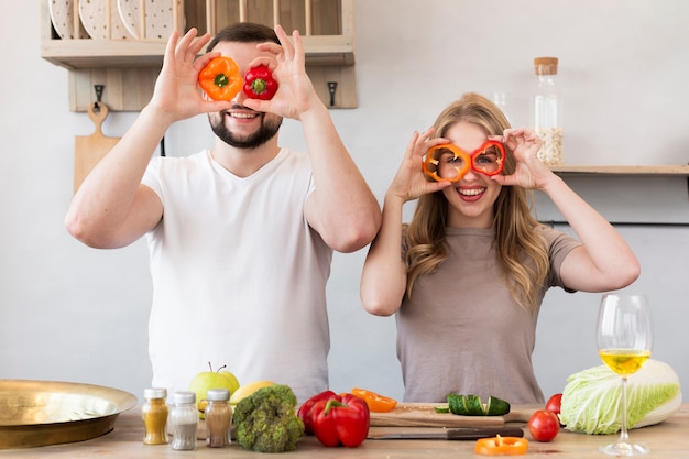 Pareja sonriente jugando con pimiento