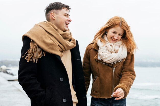 Pareja sonriente junto al lago durante el invierno