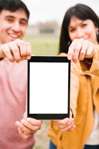 Foto gratuita pareja sonriente llevando tableta