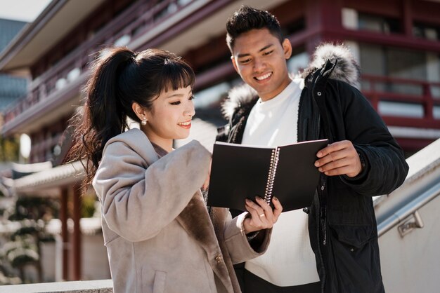 Pareja sonriente mirando un cuaderno juntos