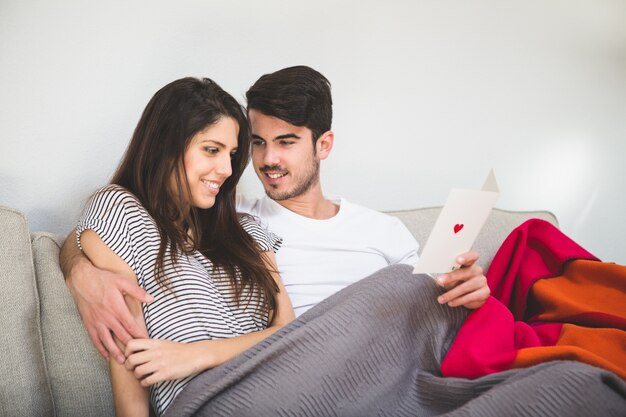 Pareja sonriente mirando una postal con un corazón