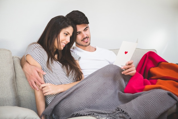 Pareja sonriente mirando una postal con un corazón