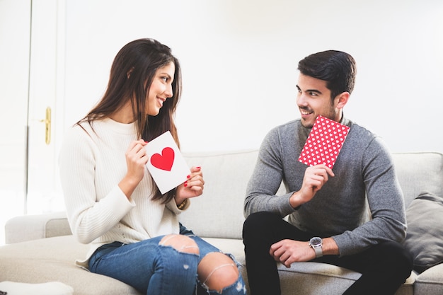 Foto gratuita pareja sonriente mirando postales con un corazón