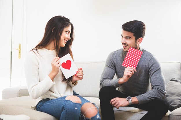 Pareja sonriente mirando postales con un corazón