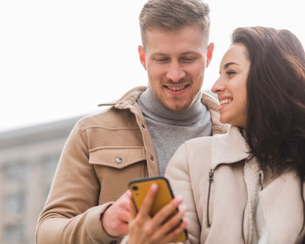 Pareja sonriente mirando smartphone