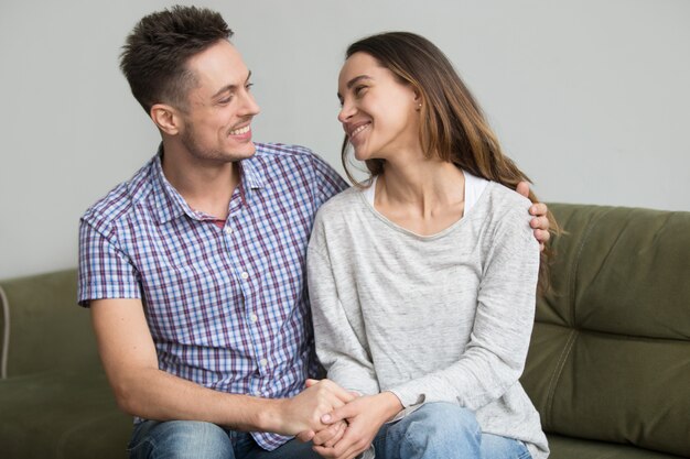 Pareja sonriente mirándose el uno al otro reconciliada después de una pelea