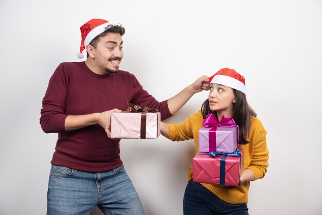 Pareja sonriente en moda de invierno con regalos sobre fondo blanco.